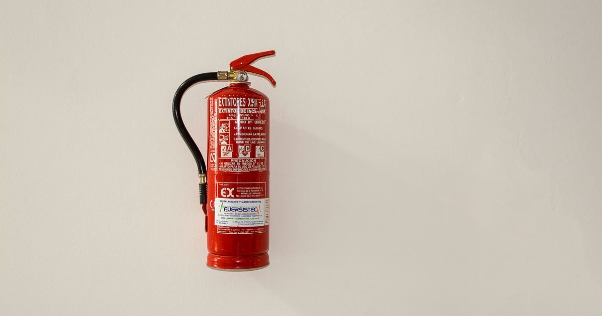 Rode brandblusser aan een lichte muur