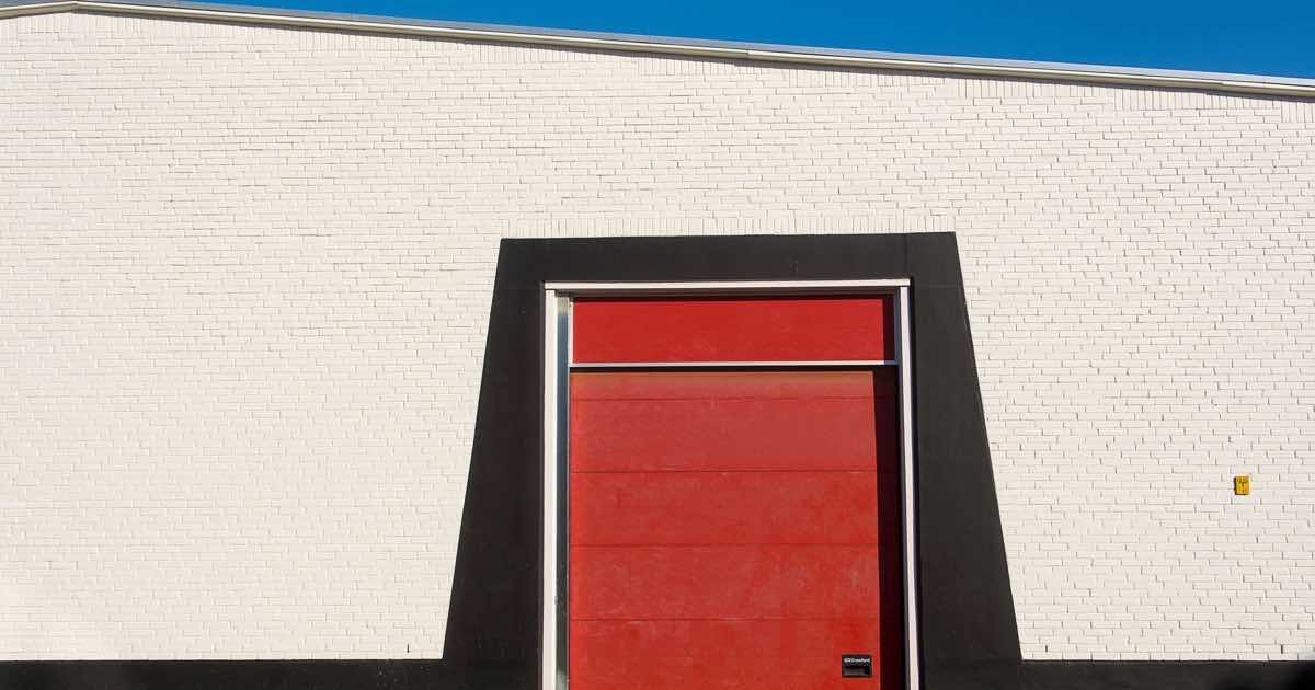 Rode garagepoort in een witte gevel