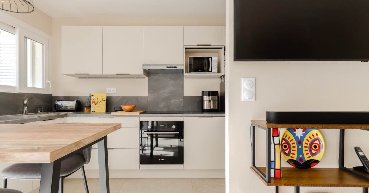 Lichte keuken met witte kasten, ingebouwde oven en een eiland met houten blad