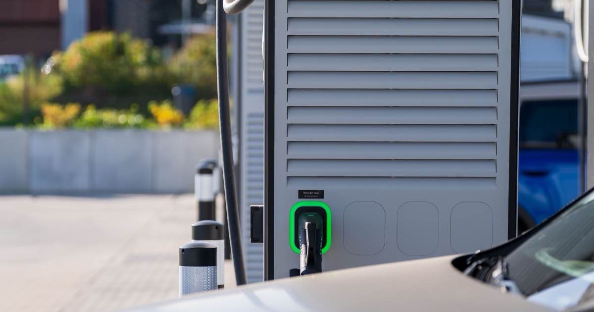 Laadpaal met aangesloten laadkabel naast een elektrische auto