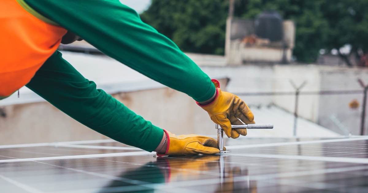 Technicus met werkhandschoenen aan een zonnepaneel