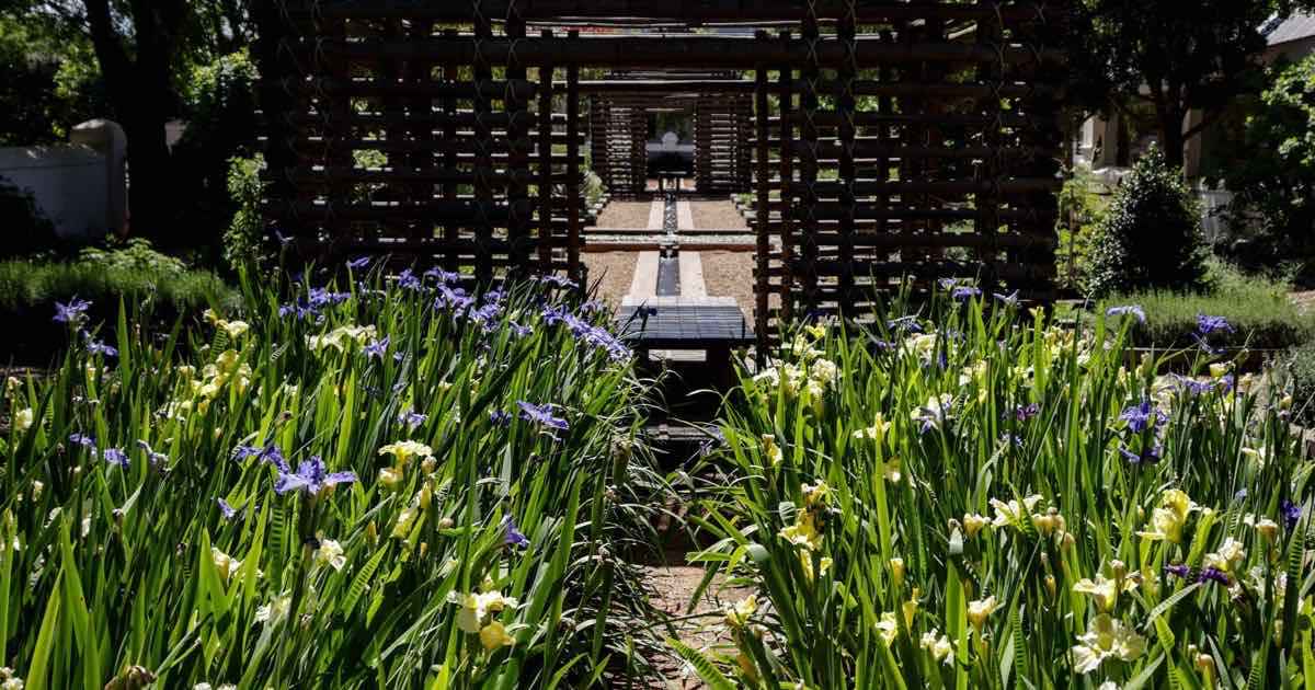 Houten tuinpaviljoen achter bloeiende planten
