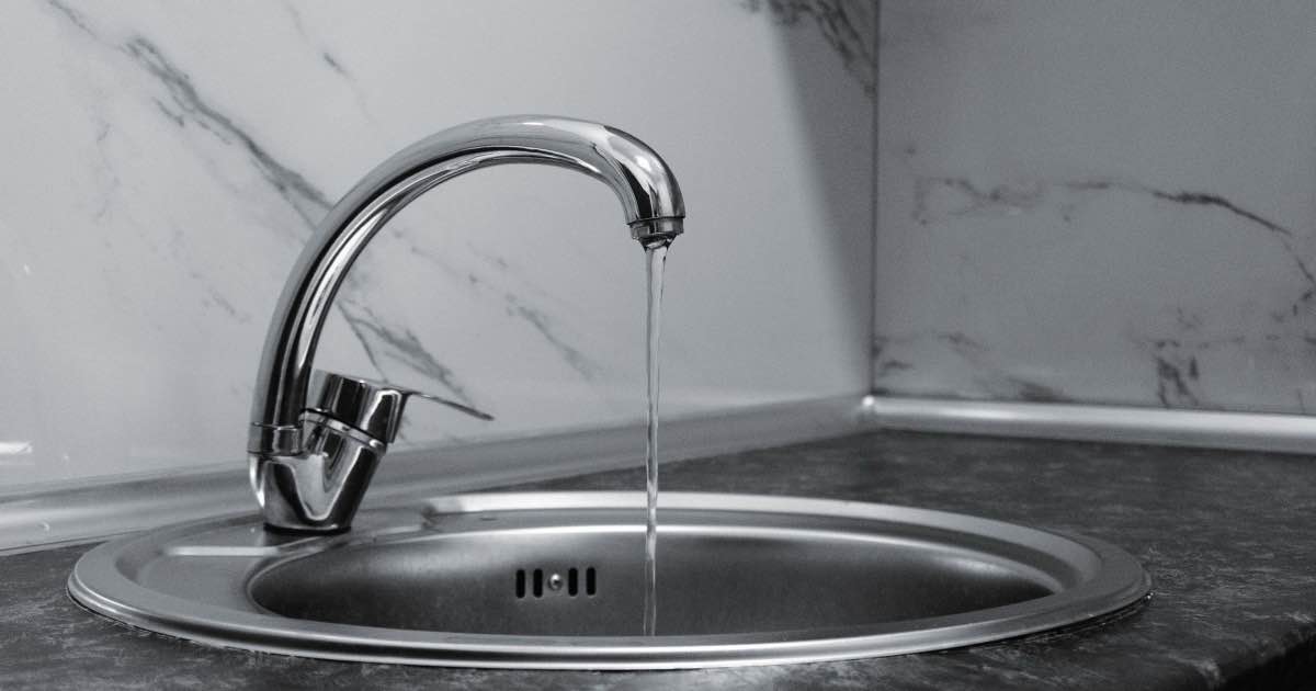 Water loopt uit een keukenkraan in een inox spoelbak